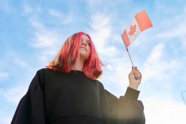 Studentessa adolescente con bandiera canadese in mano, cielo blu con sfondo nuvole. — Foto Stock