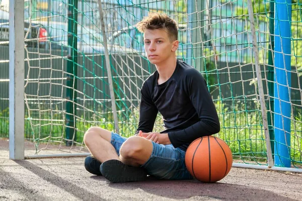 Guy adolescent avec ballon, terrain de basket-ball extérieur fond de la ville — Photo