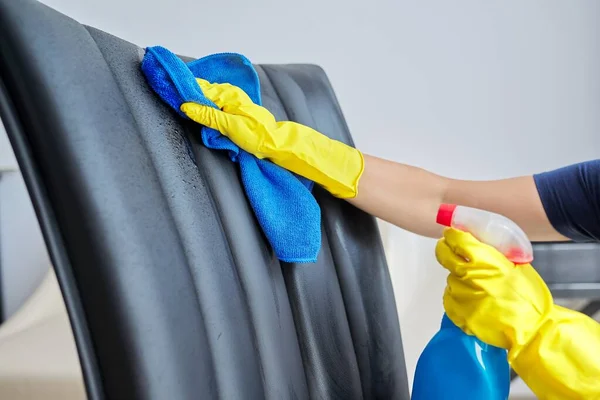 Limpieza del hogar, mujer en guantes con trapo y spray con detergente lavando silla de cuero —  Fotos de Stock