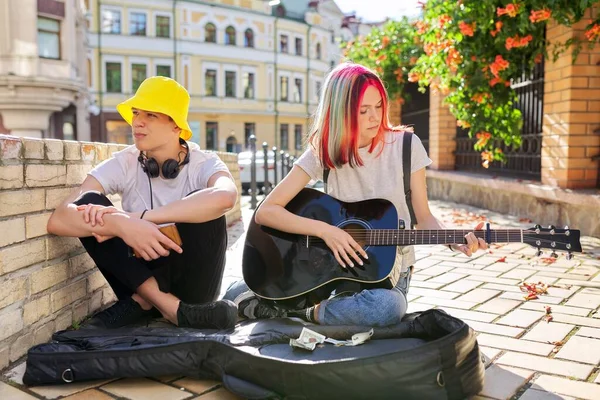 Pár tinédzser hippi utcai zenész, akik zenével keresnek pénzt. — Stock Fotó