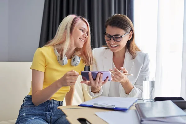 Consejero profesional mira la pantalla del teléfono inteligente con la chica estudiante —  Fotos de Stock