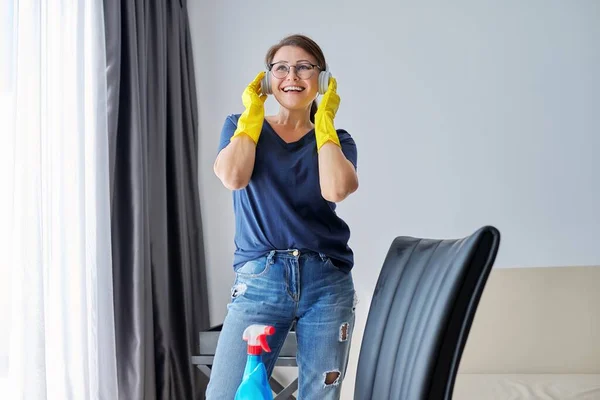 Maturo donna positiva in cuffie guanti di gomma facendo pulizia della casa — Foto Stock