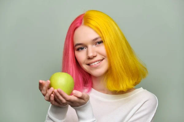 Huvudskott av vackra leende tonåring flicka med vitt leende med tänder, hålla ett äpple — Stockfoto