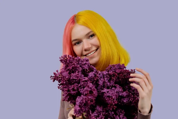 Tonårstjej med färgat rosa gult hår som håller lila blommor i händerna — Stockfoto
