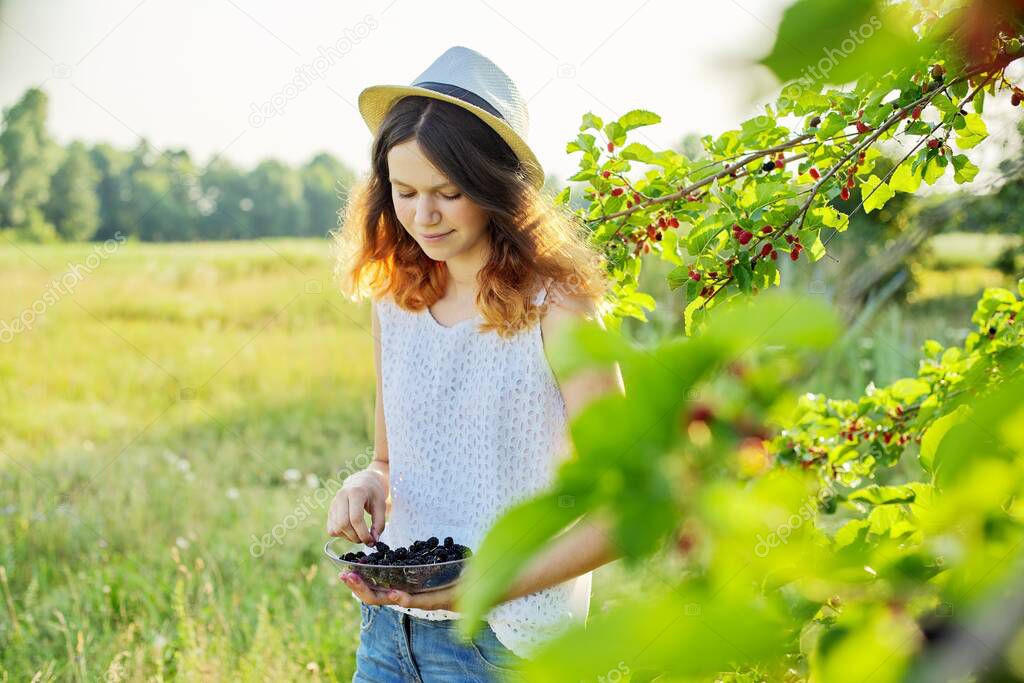 Girl teenager eating delicious healthy mulberries from the tree
