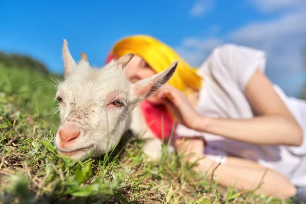 Adolescente chica con un poco de cabra blanca en el césped, bozal animal de cerca — Foto de Stock