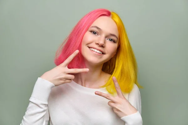 Hlava záběr módní krásné dospívající dívka ukazuje vítězství gesto s prsty, žena s módní barvené vlasy na zeleném pozadí — Stock fotografie
