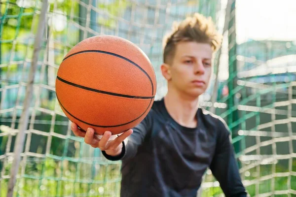 Närbild basket boll i handen på tonåring kille — Stockfoto