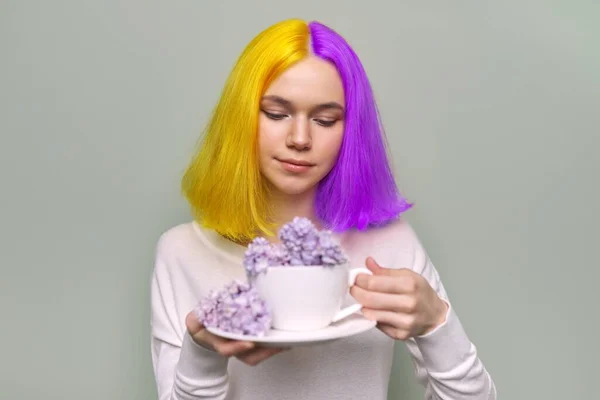 Chica adolescente con el pelo teñido de color amarillo púrpura sosteniendo flores de color lila en las manos — Foto de Stock