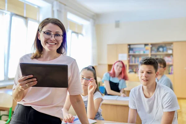 Portrét učitelky ve škole, usmívající se žena v brýlích s digitálním tabletem — Stock fotografie