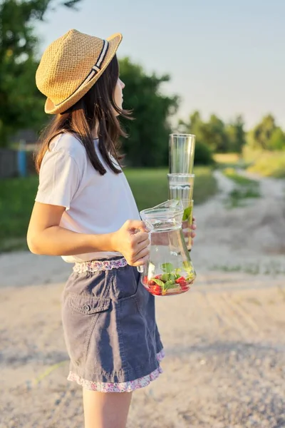 Dívka s džbánem s domácím jahodovým mátovým nápojem a prázdnými sklenicemi — Stock fotografie