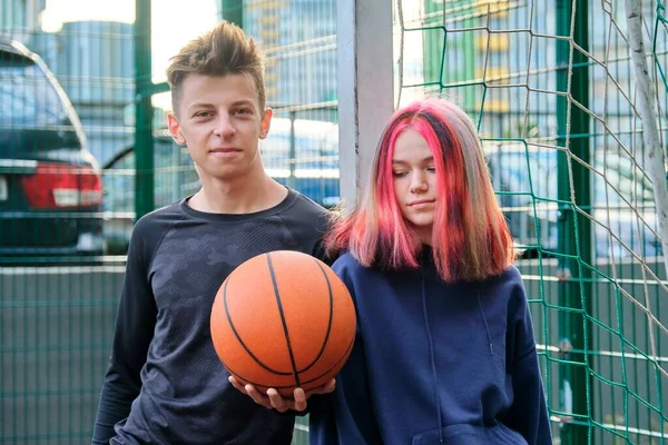 Outdoor portret van tiener jongen en meisje op basketbalveld met bal — Stockfoto