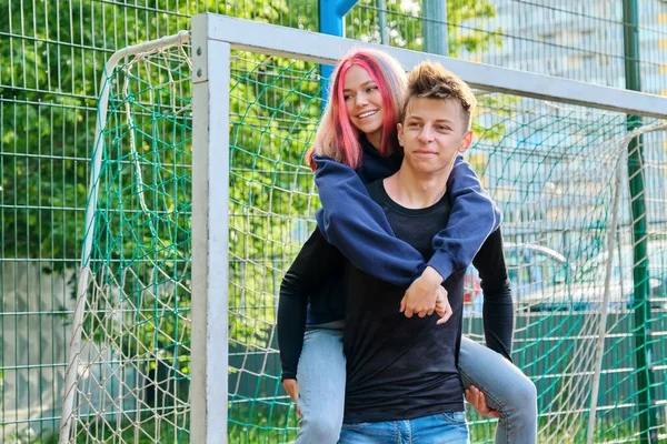 Pár tinédzser srác és lány szórakozik egy szabadtéri kosárpályán — Stock Fotó