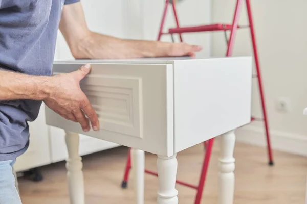 Montage eines hölzernen weißen Nachttisches zu Hause, Nahaufnahme einer Arbeiterhand — Stockfoto