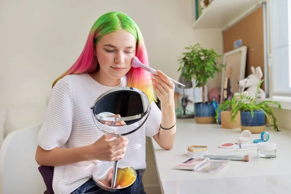 Chica adolescente con el pelo teñido haciendo maquillaje mirando en el espejo —  Fotos de Stock