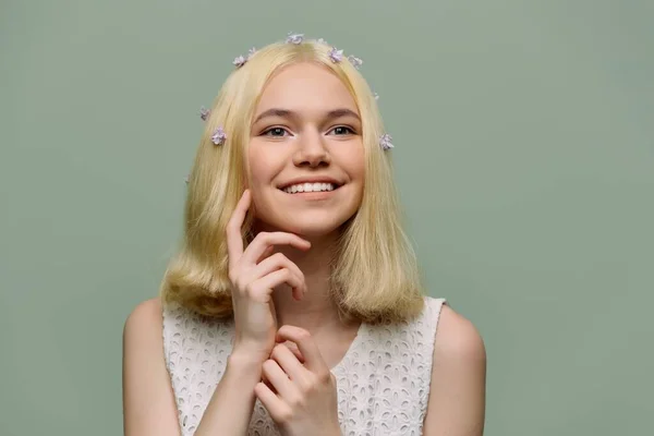 Joven chica tierna adolescente con flores de color lila en el pelo rubio sobre fondo verde — Foto de Stock