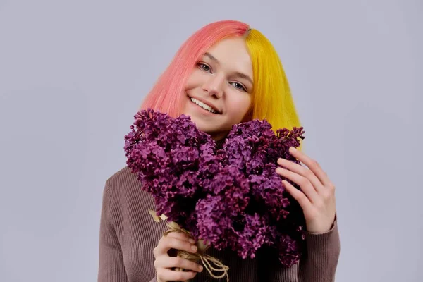 Tonårstjej med färgat rosa gult hår som håller lila blommor i händerna — Stockfoto