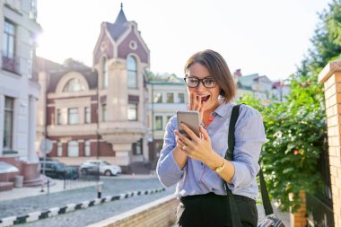 Gülümseyen kadın video görüşmesi yapıyor, akıllı telefon ekranına bakıyor ve konuşuyor.