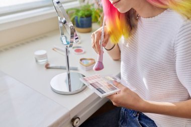 Renkli saçlı genç kız gözlerini dekoratif gölgelerle boyuyor.