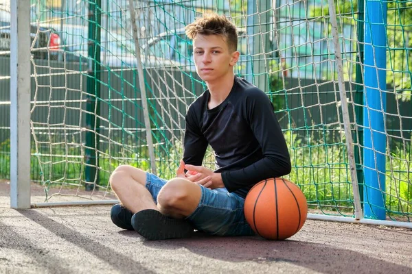 Guy teenager s míčem, venkovní basketbal městské hřiště pozadí — Stock fotografie