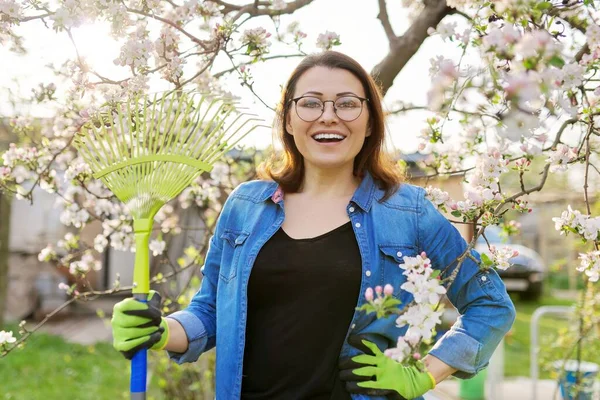 Весеннее садоводство, портрет зрелой улыбающейся женщины с грабли, смотрящей в камеру — стоковое фото