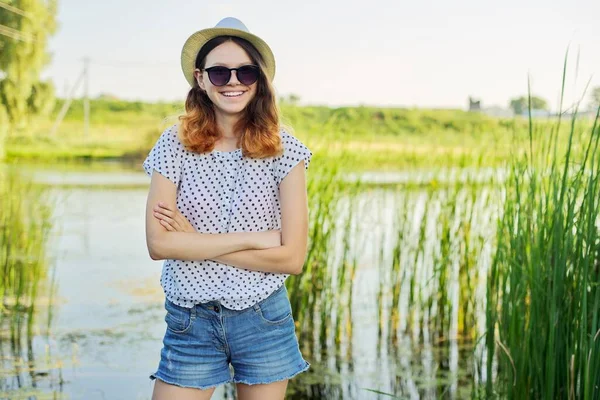 Retrato de país ao ar livre da menina adolescente em óculos de sol chapéu perto da lagoa nos juncos — Fotografia de Stock