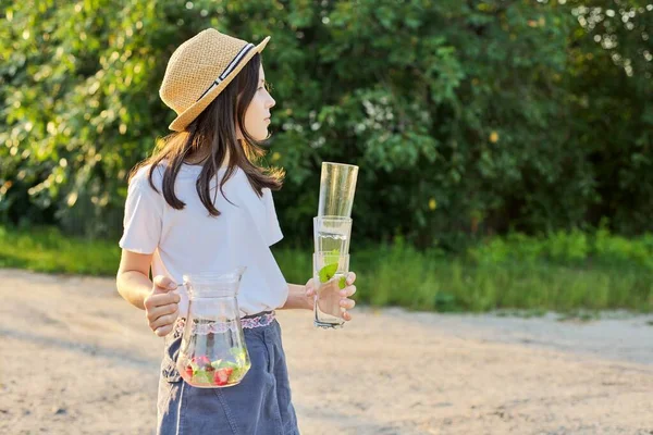 Girl with jug with homemade strawberry mint drink and empty glasses — Stock Photo, Image