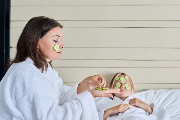 Mãe e filha adolescente cuidando do rosto usando cosméticos naturais e pepino — Fotografia de Stock