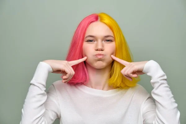 Grimacing teenager dívka, fena s módní barvené vlasy na zeleném pozadí — Stock fotografie