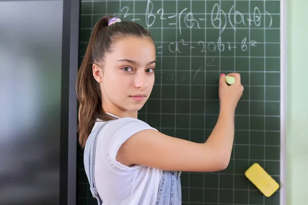 Retrato de niña estudiante de adolescente 13 años de edad en la escuela cerca de pizarra — Foto de Stock