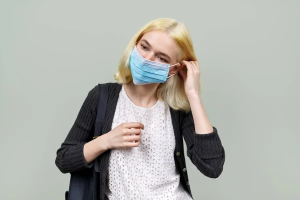 Mujer joven con máscara de protección médica. Adolescente chica en verde pastel fondo — Foto de Stock