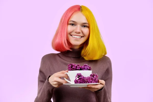 Lilac blommor i vit kopp i händerna på ung kvinna på rosa bakgrund — Stockfoto