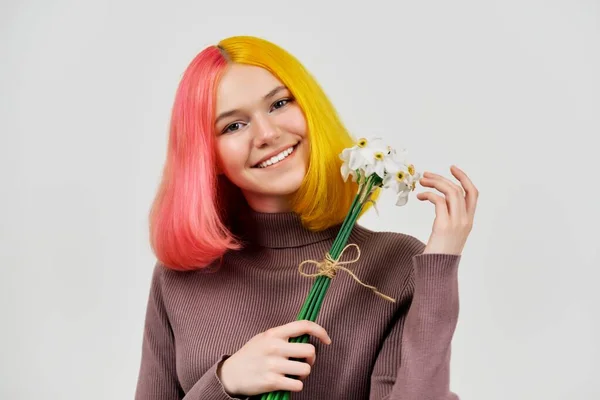 Leende glad trendig tonåring flicka med bukett av vita påskliljor blommor på ljus bakgrund — Stockfoto