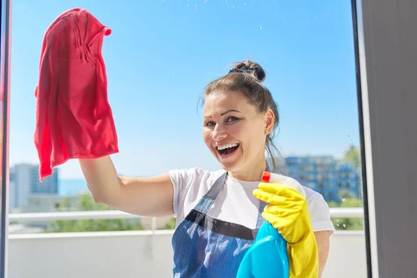 Portret van volwassen positieve vrouw wassen venster — Stockfoto