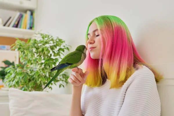 Tonårstjej kysser en papegoja. Närbild ansikte kvinna och grön kväkare papegoja — Stockfoto