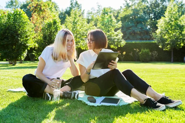 Žena učitel mluví s dospívající studentka sedí na trávě — Stock fotografie