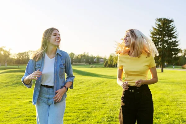 Lindas mulheres jovens em execução ativa, gramados verdes do parque ao pôr do sol — Fotografia de Stock