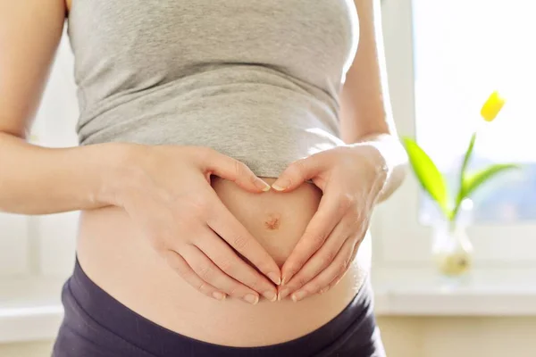 Portrait of young beautiful pregnant woman showing love heart with hands on stomach — Stock Photo, Image