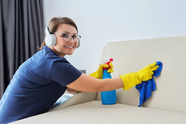 Frau beim Hausputzen, Frau mit Kopfhörer und Handschuhen mit Waschmittel — Stockfoto