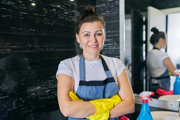 Portrait de la femme positive d'âge moyen dans des gants de tablier faisant le nettoyage à la maison — Photo