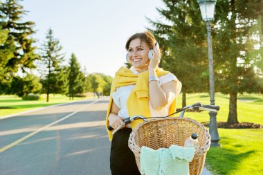 Parkta bisiklet süren güzel, aktif, olgun bir kadın.