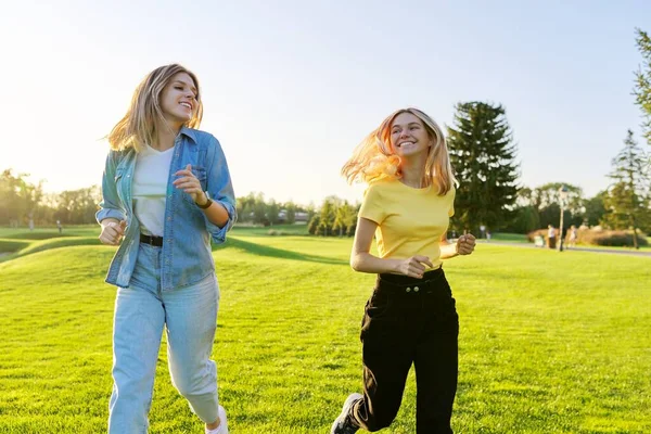 Lindas mulheres jovens em execução ativa, gramados verdes do parque ao pôr do sol — Fotografia de Stock