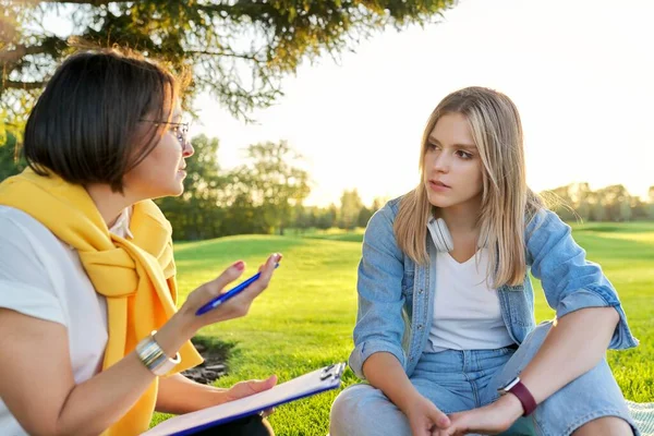 Разговор молодой женщины с психологом, социальным работником, на открытом воздухе на встрече в парке на газоне — стоковое фото