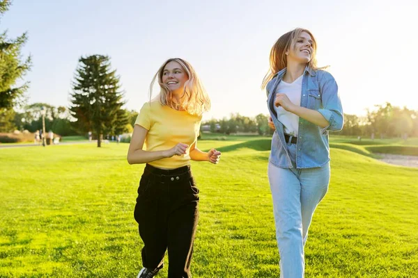 Lindas mulheres jovens em execução ativa, gramados verdes do parque ao pôr do sol — Fotografia de Stock