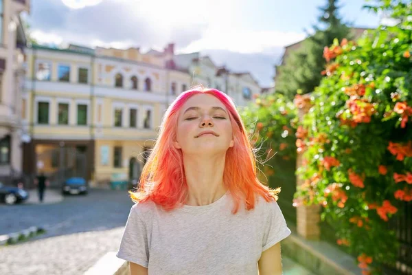 Young happy woman with closed eyes, on sunny summer city street