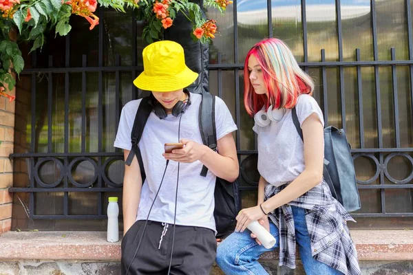 Adolescentes estudiantes chico y chica mirar en la pantalla del teléfono inteligente —  Fotos de Stock