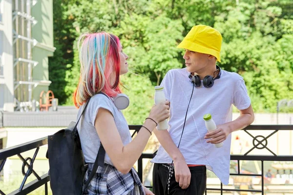 Couple of college students talking having rest drinking milk drink in bottle outdoors — Stock Photo, Image