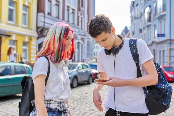 Adolescentes estudiantes chico y chica mirar en la pantalla del teléfono inteligente —  Fotos de Stock