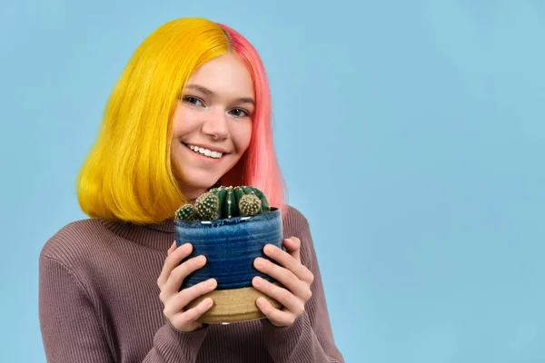 Sorrindo adolescente cabeça tiro com tingido colorido cabelo segurando pote com cacto — Fotografia de Stock