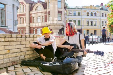 Mutlu gençler çift olarak akustik gitar çalıyorlar.